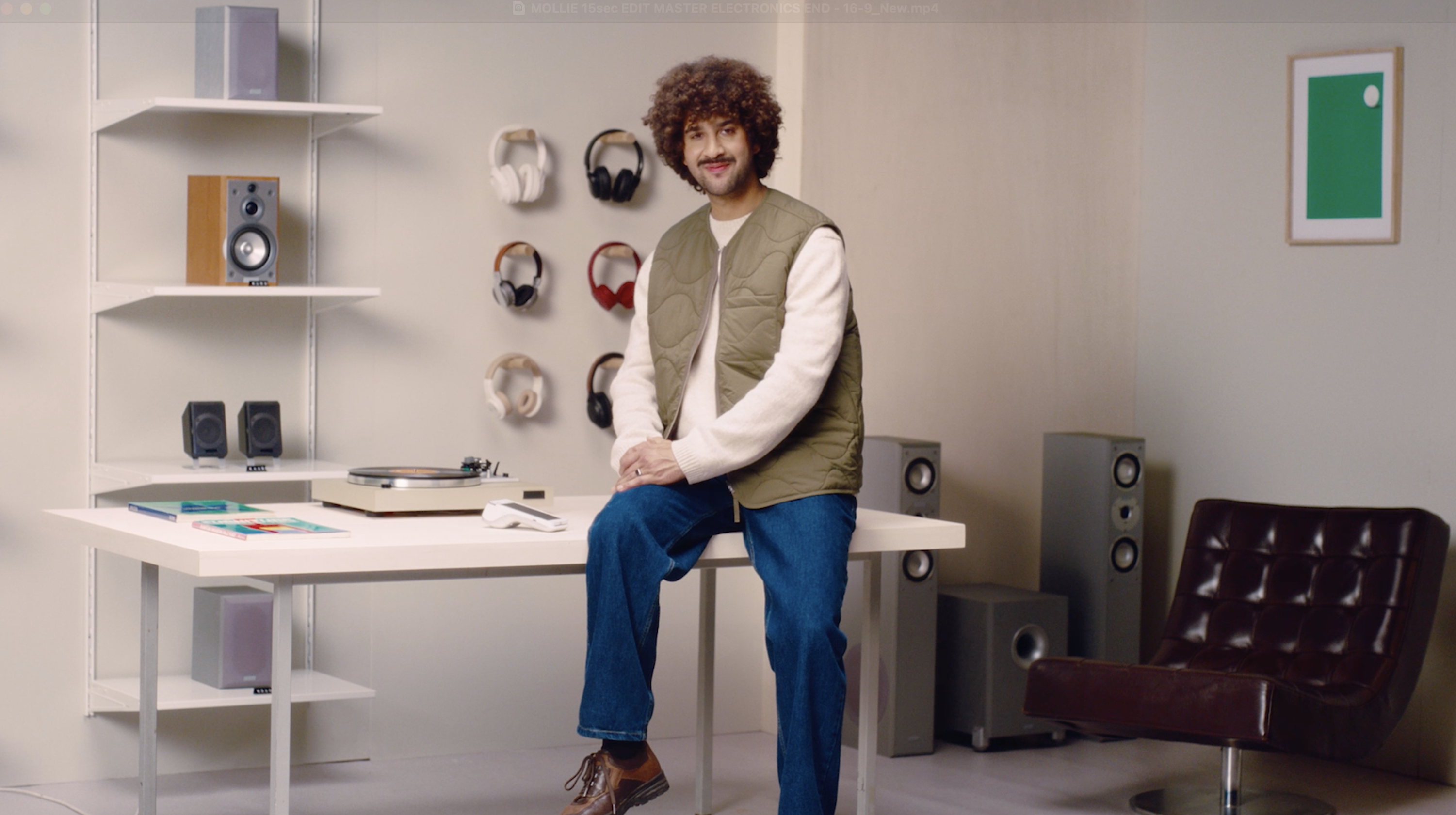 art direction - Studio Gerritsen-Bart man sitting on a table in a electronics store with a brown chair and a green print on the wall