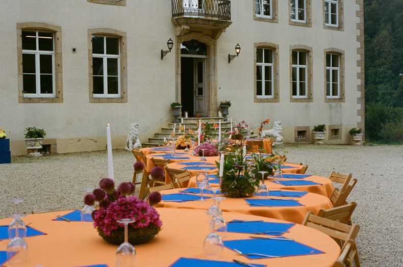 event design and art direction - Studio Gerritsen-Bart playful dinner setting in Belgian wedding with round tables with orange table cloths